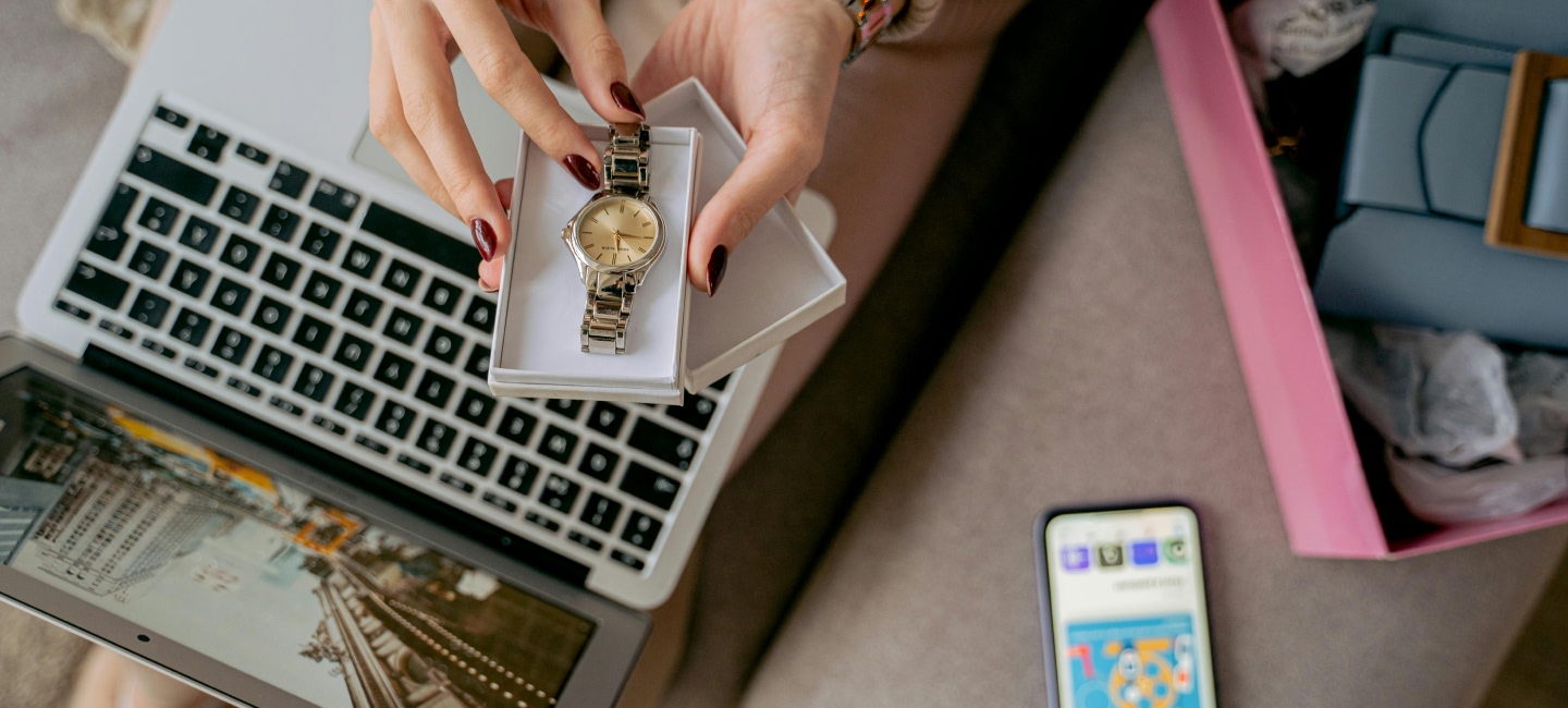 Manos de mujer con un reloj de lujo frente a un ordenador.